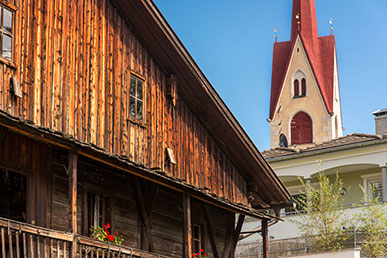 Una casa in legno e la chiesa di Monguelfo