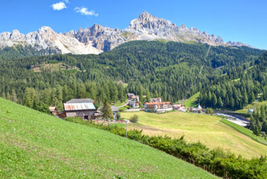 Boschi e prati verdi in Val d'Ega e in lontananza il Catinaccio 