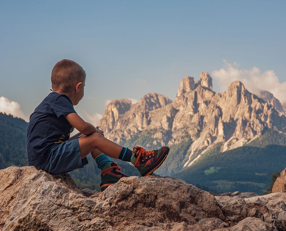 A child standing on a rock looking out over the Alps
