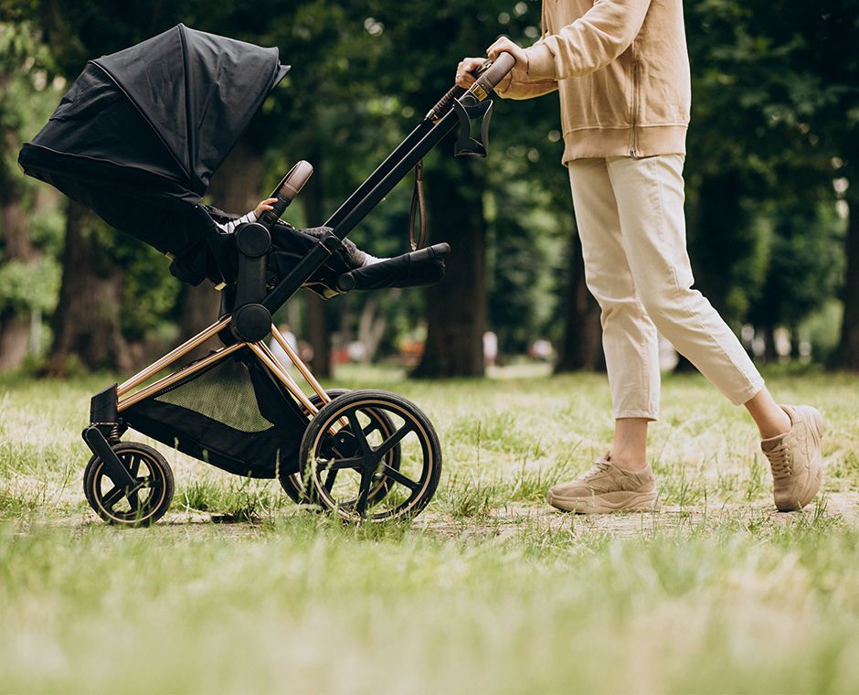 Young mother walking with a stroller in the park