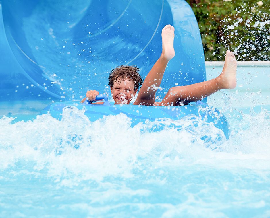 An 8-year-old riding inflatable rings on water slides at an aqua park.