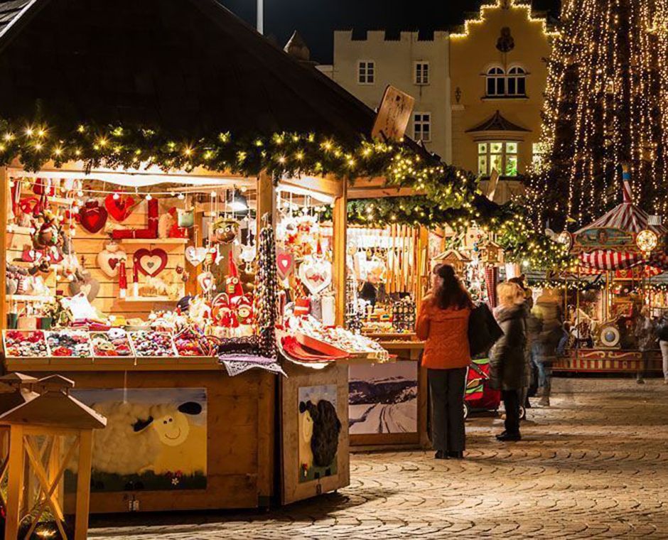Christmas Market in Bressanone in Cathedral Square, stalls around the baroque cathedral and visitors on the snowy square