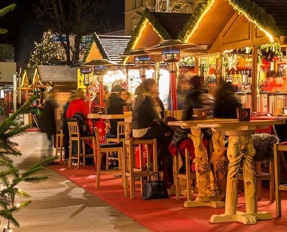 Christmas Market in Brunico near Plan de Corones – wooden stalls, lights, and a snowy landscape