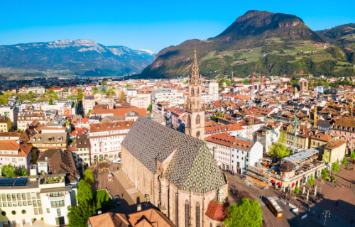 Aerial view of Bolzano with the cathedral, the roofs of the old town and the mountains in the background.