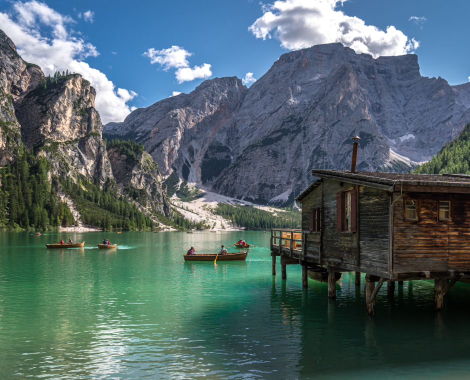Lago di Braies con barche a remi, baita in legno sull’acqua e montagne dolomitiche sullo sfondo.