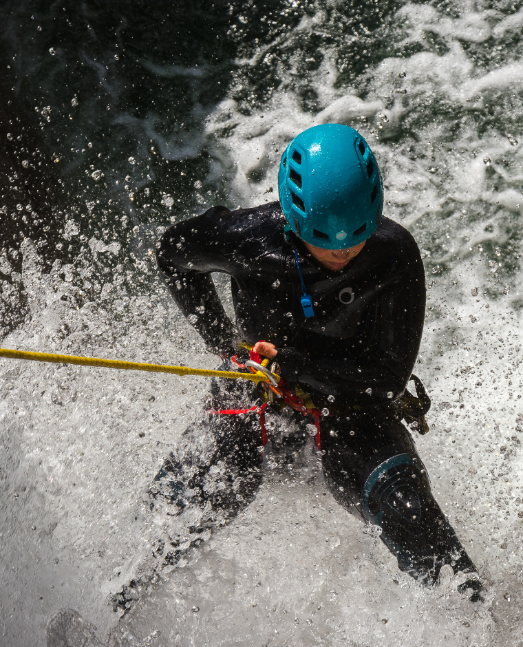 Un uomo fa rafting su un fiume, con l'acqua che schizza ovunque.