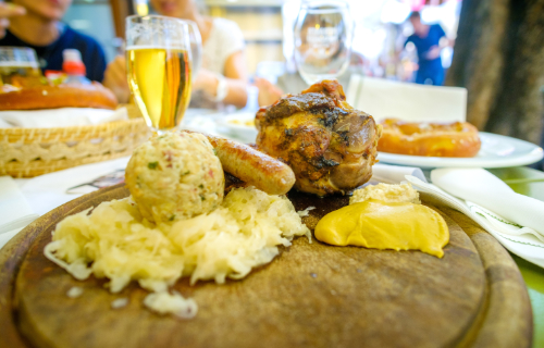 A typical South Tyrolean dish with roasted ham hock, sausage, dumplings, sauerkraut and mustard, served on a wooden board.