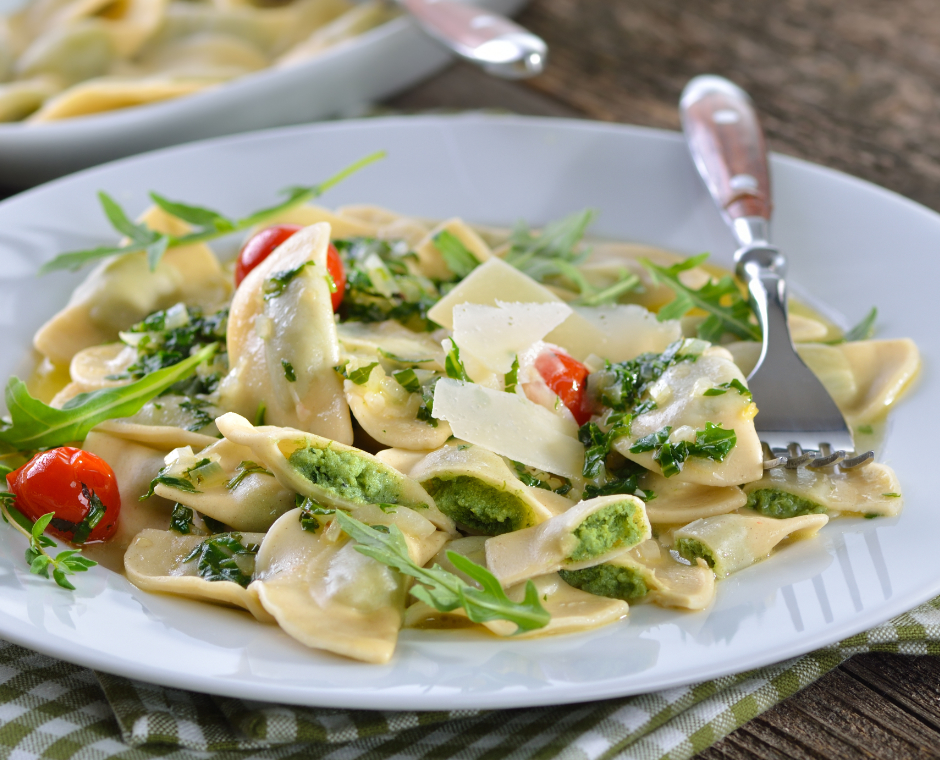 Ravioli ripieni alle erbe con pomodorini, rucola e scaglie di formaggio.