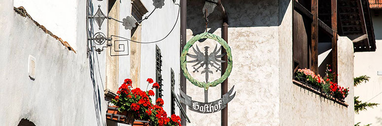 Foto eines Aushängeschildes eines typischen Restaurants von Andrian mit Tiroler Adler und Lorbeerkranz