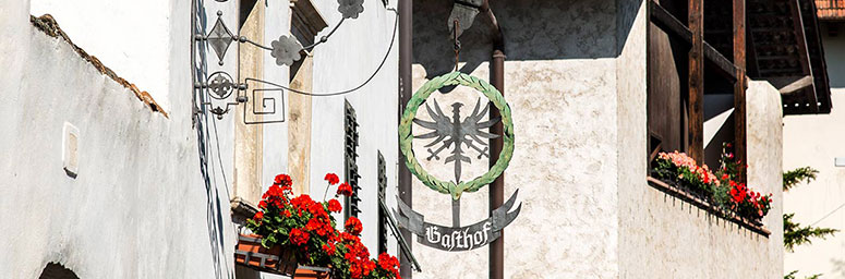 Foto eines Aushängeschildes eines typischen Restaurants von Andrian mit Tiroler Adler und Lorbeerkranz