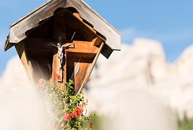 Kruzifix in St. Kassian mit Bergen im Hintergrund