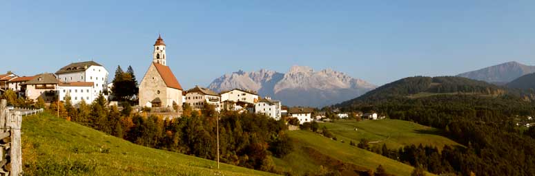 Blick auf das Dorf Deutschnofen im Sommer mit Berglandschaft im Hintergrund.