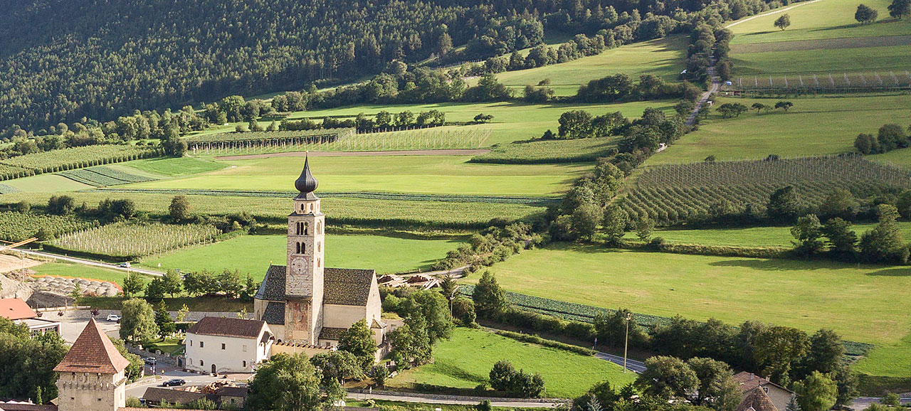 Vista dall’alto della Chiesa di San Pancrazio a Glorenza circondata da prati verdeggianti