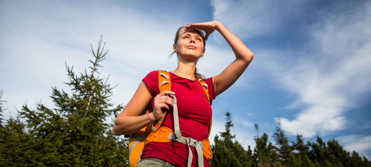 Woman dressed in red with a backpack looking in the distance