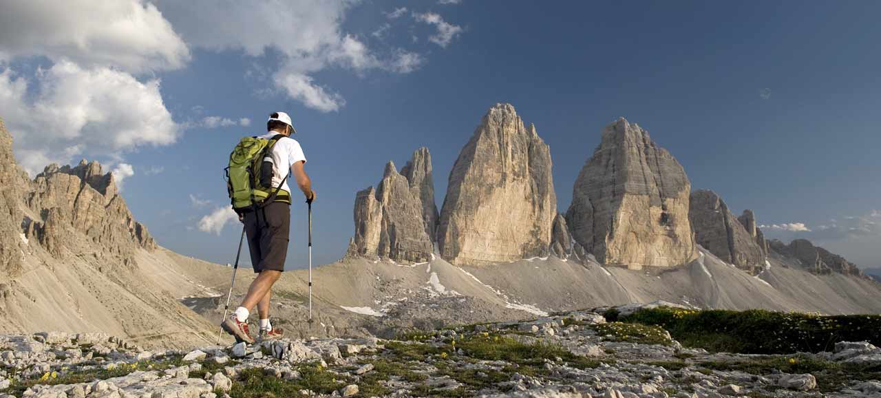 Uomo che fa un'escursione in montagna con le cime di Lavaredo sullo sfondo