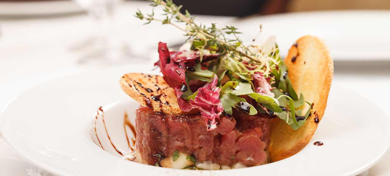 Nahaufnahme von einem Gourmet-Gericht: Tartar mit Gemüse, Croutons und Balsamico-Essig