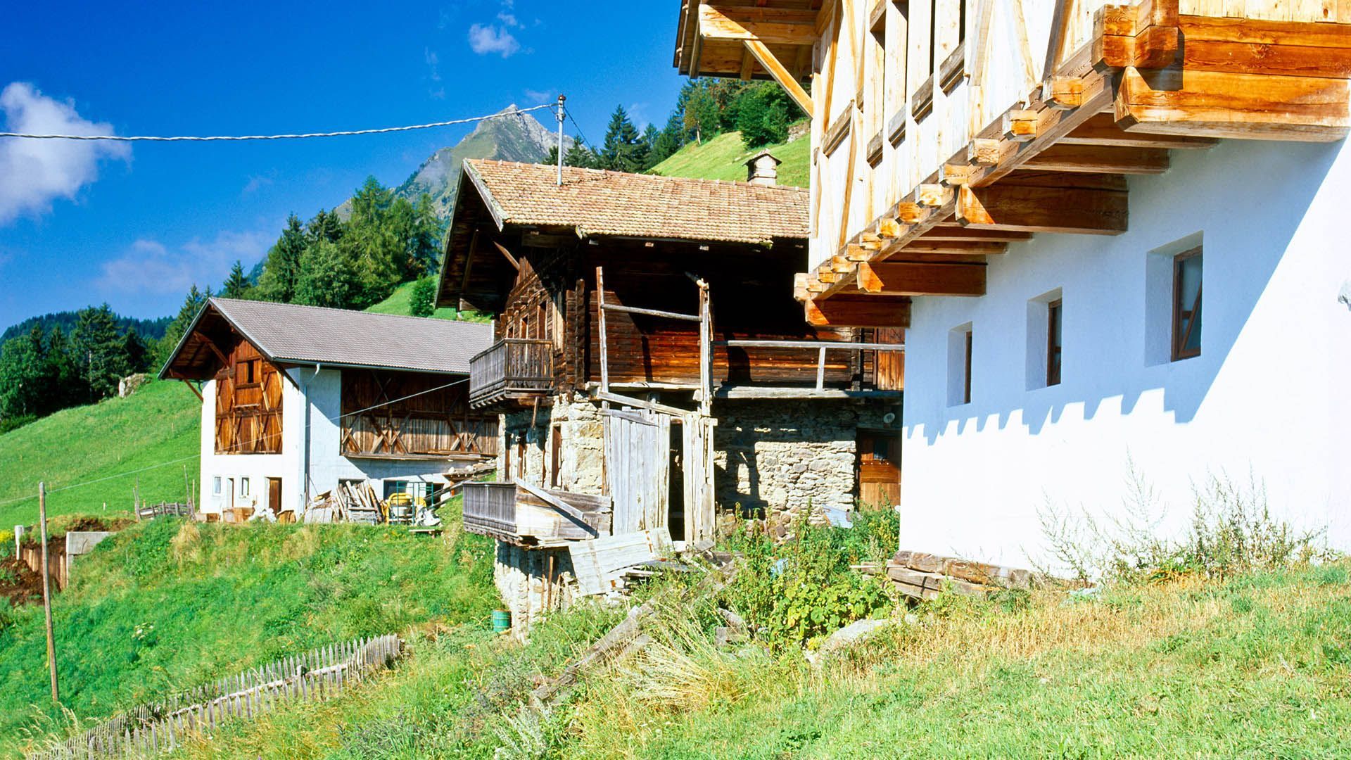 Ancient wooden and stone farmsteads in Val Passiria with mountain backdrop and alpine summer landscape