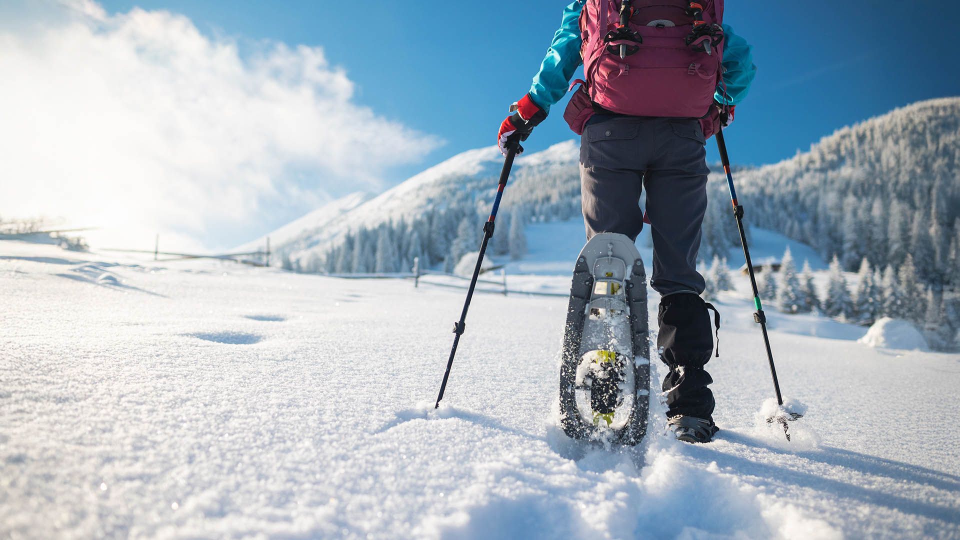 Schneeschuhwanderer geht auf einem verschneiten Weg durch die Berge.