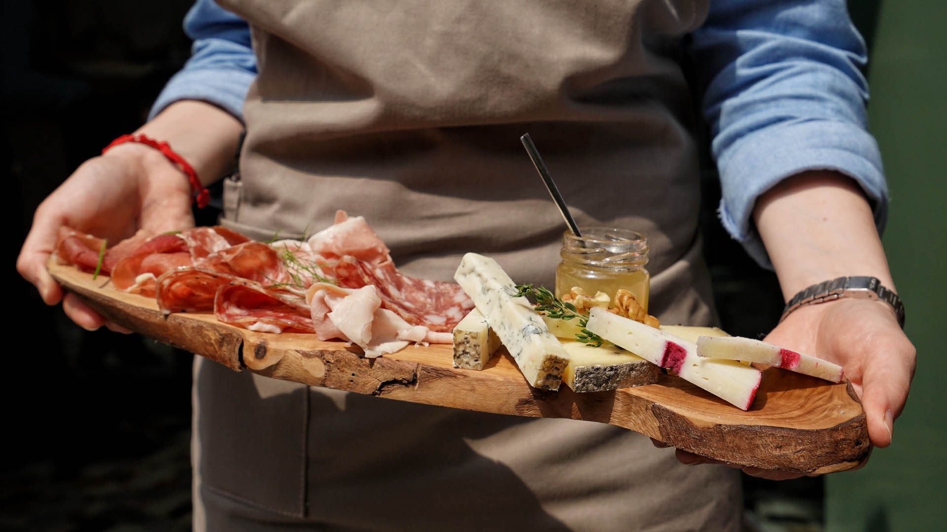 Brett mit Wurst, Käse und Honig, serviert von einem Kellner