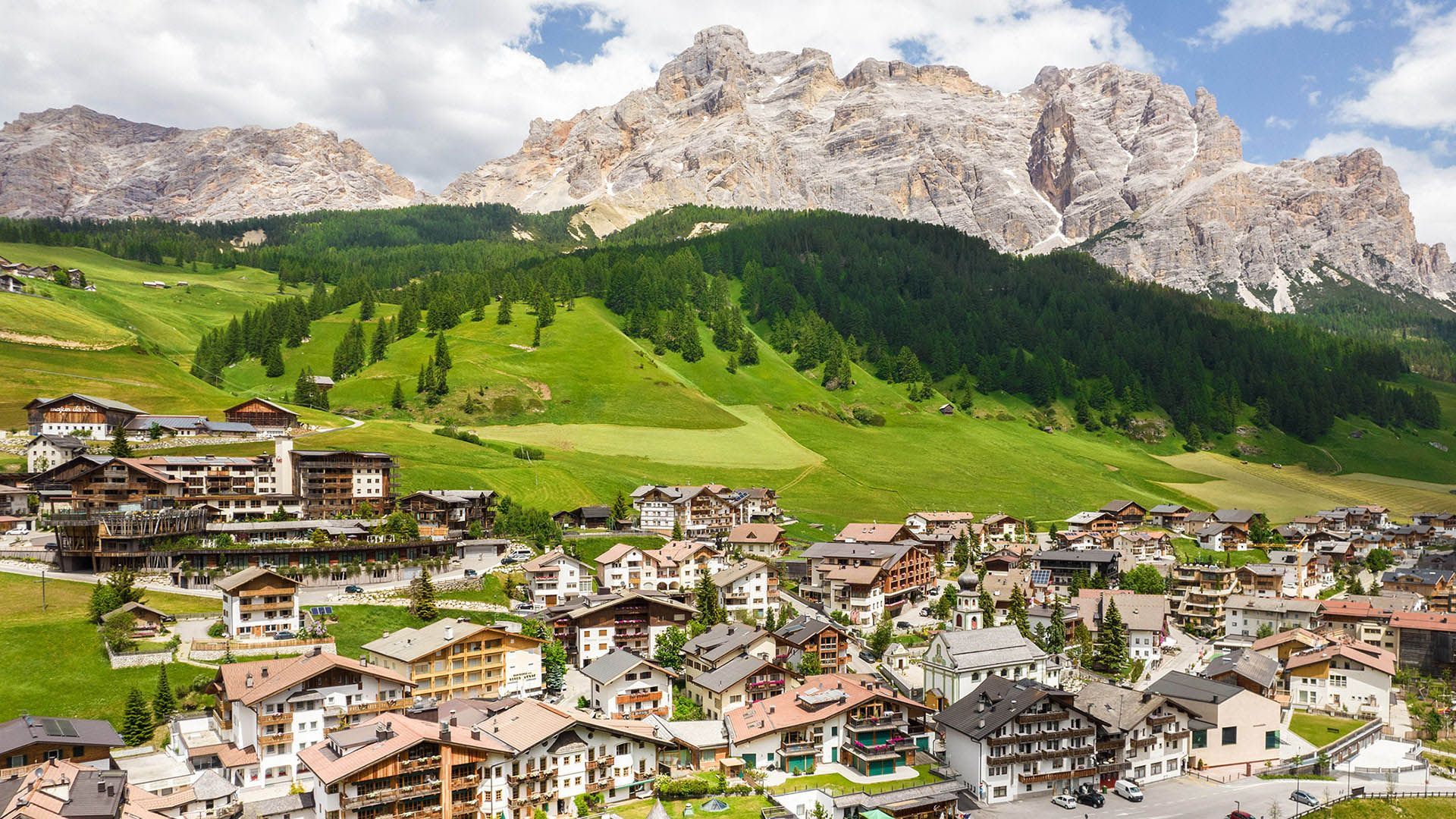 The village of San Cassiano in Alta Badia, surrounded by green meadows and Dolomite peaks