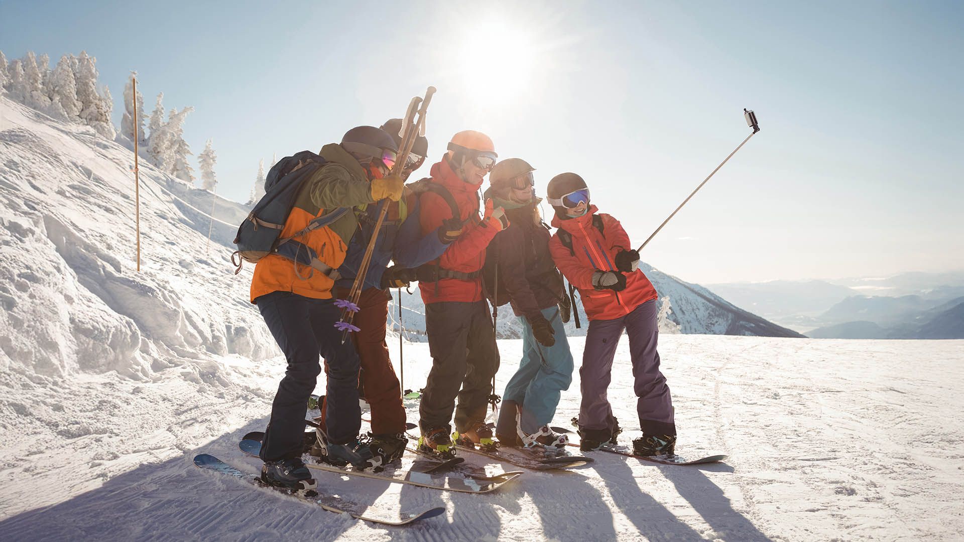 Freundesgruppe mit Ski und Snowboard macht ein Selfie auf den verschneiten Pisten.