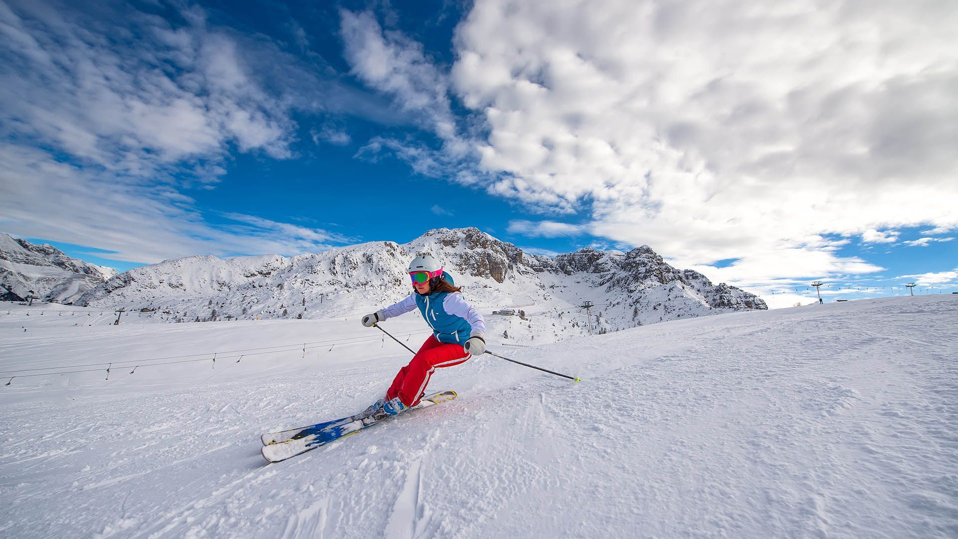 Skiier in action on a snow-covered slope with mountains in the background in South Tyrol.