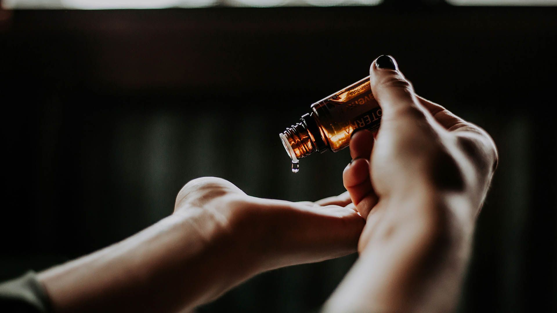 A drop of essential oil falls onto the palm of your hand in a moment of well-being.  