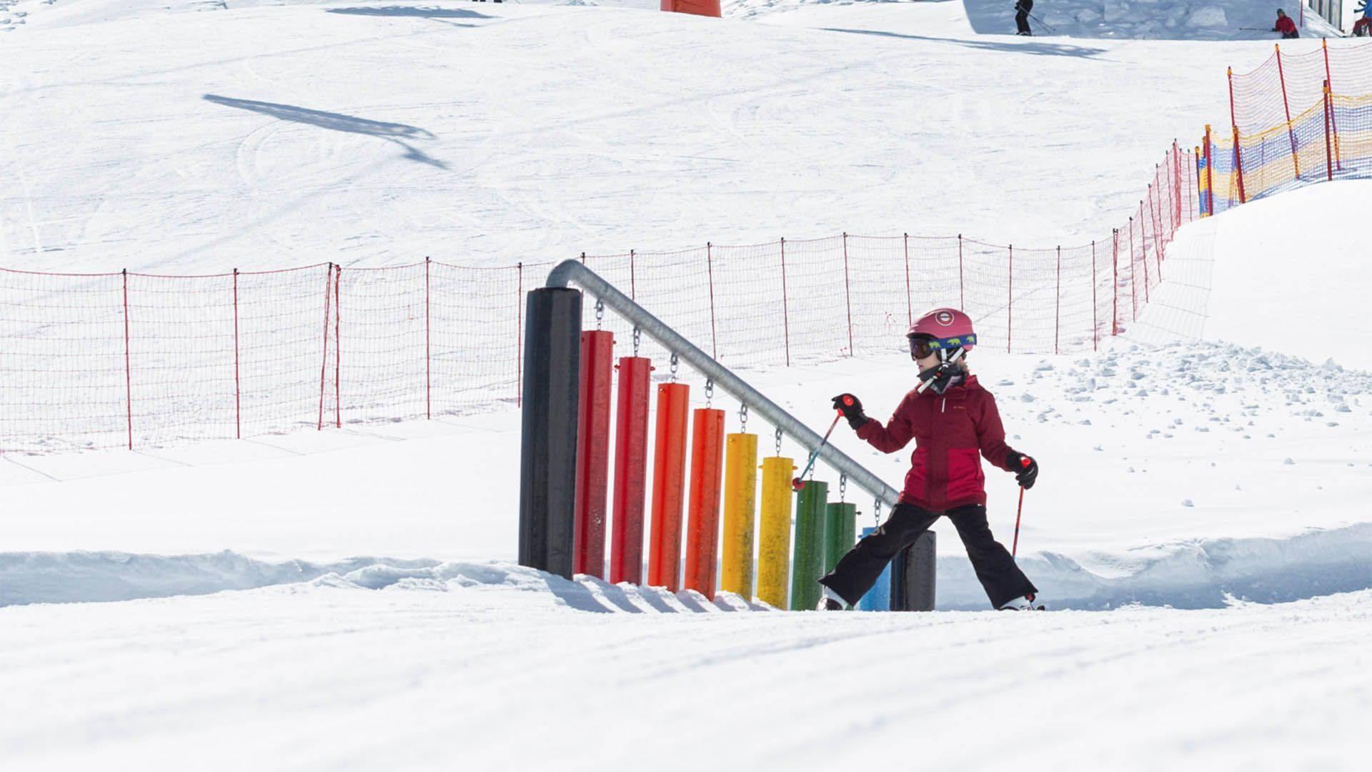 Child skiing near a colourful xylophone in the snow, children's slope in Val Venosta