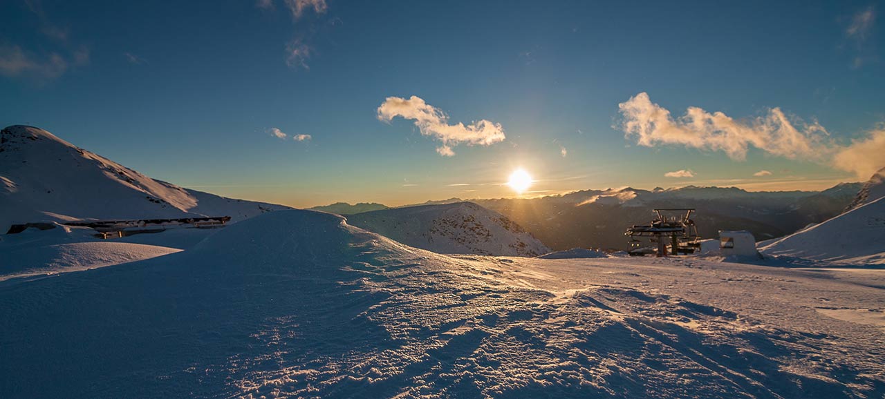 Winterpanorama bei untergehenden Sonne auf einer Skipiste bei Meran