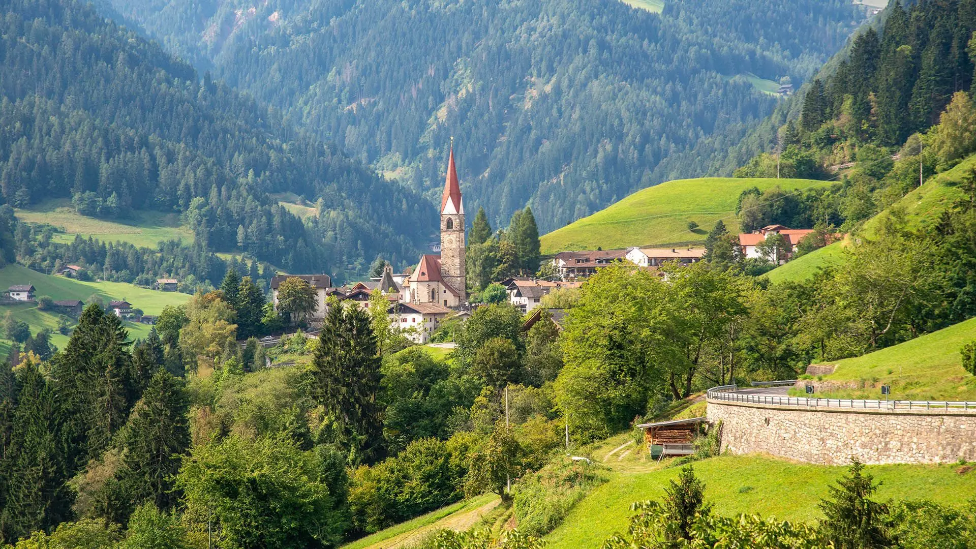 Das Dorf St. Pankraz mit seiner Kirche zwischen Wäldern und grünen Hängen im Ultental