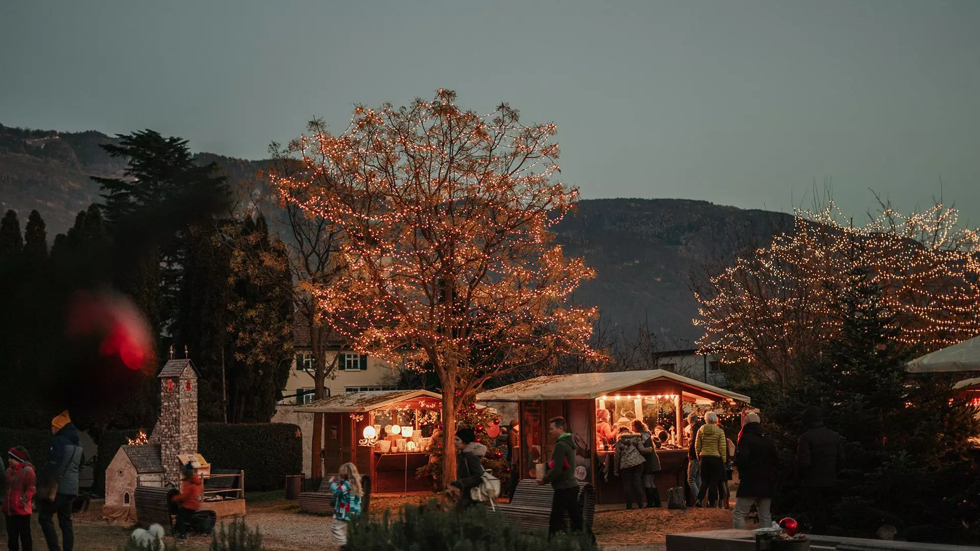 Panoramablick auf Lana in Südtirol mit Häusern, Kirchturm und Bergen im Hintergrund