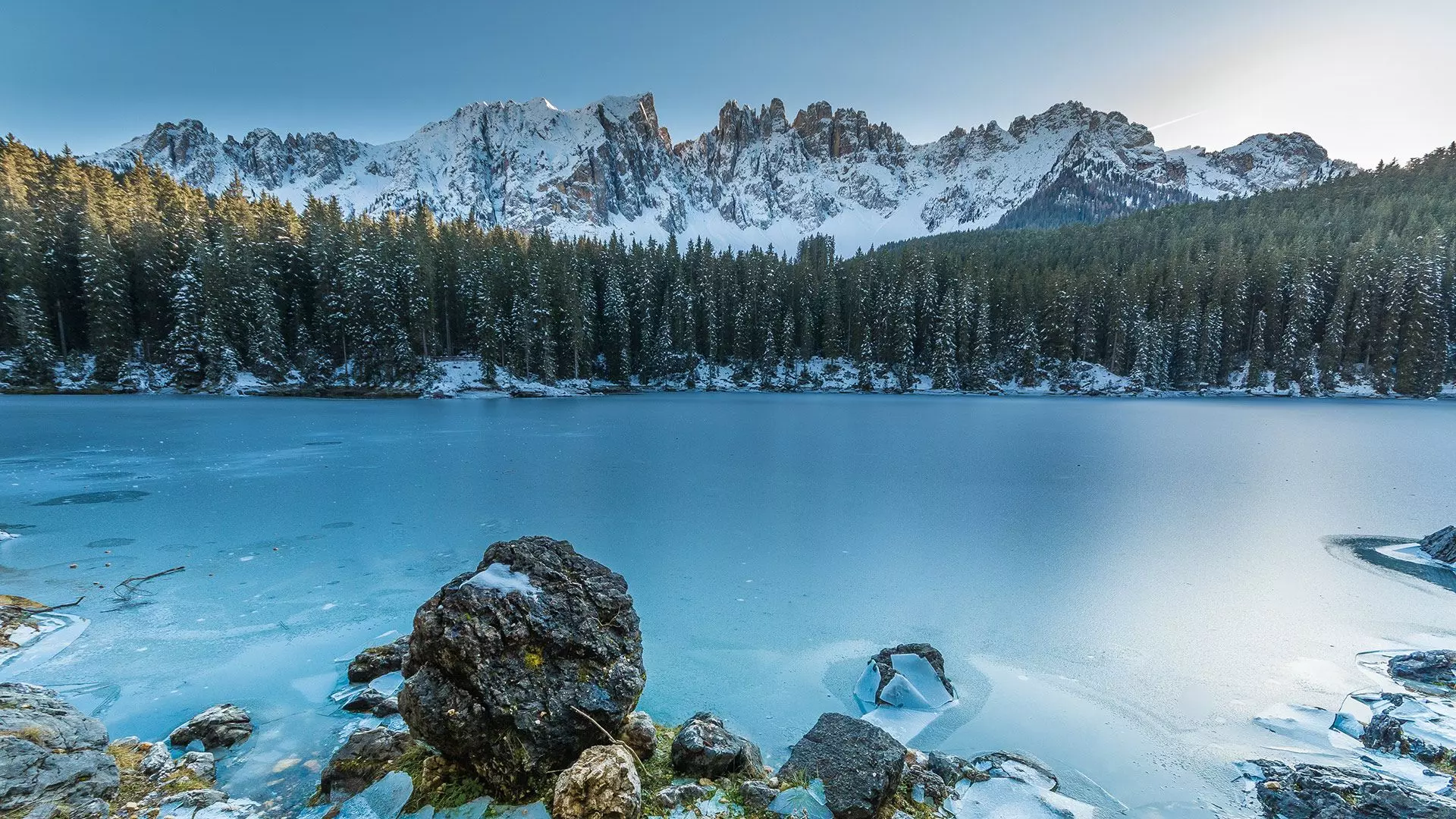Karersee mit türkisfarbenem Wasser und Blick auf den Latemar zwischen Wäldern und Dolomiten